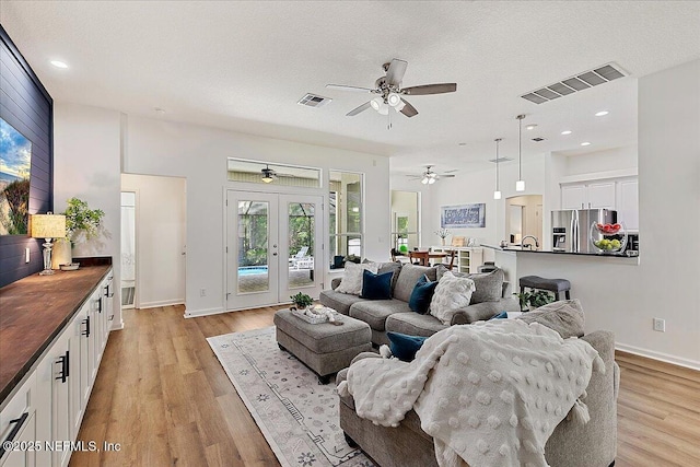 living area with french doors, ceiling fan, plenty of natural light, light wood-style flooring, and recessed lighting