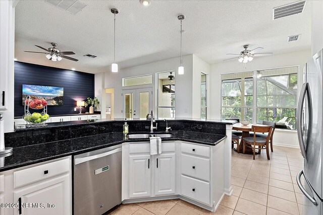 kitchen with appliances with stainless steel finishes, a ceiling fan, a sink, light tile patterned floors, and a textured ceiling