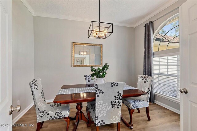 dining room featuring wood finished floors, a chandelier, baseboards, ornamental molding, and a textured ceiling