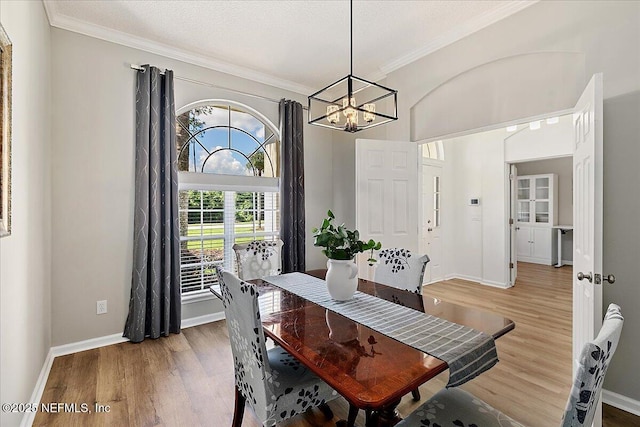 dining room featuring a chandelier, wood finished floors, crown molding, and baseboards