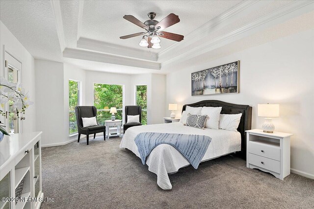 bedroom with a tray ceiling, carpet flooring, ornamental molding, baseboards, and a ceiling fan