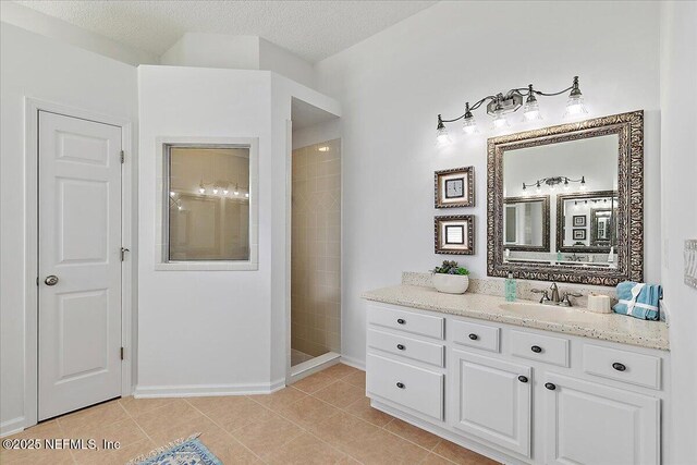 full bathroom with walk in shower, vanity, tile patterned floors, baseboards, and a textured ceiling