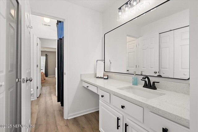 bathroom featuring wood finished floors, baseboards, and vanity