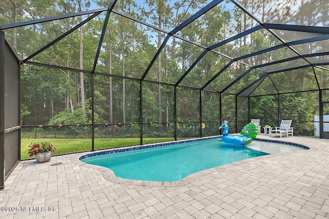 view of pool featuring a patio area, glass enclosure, and a pool with connected hot tub
