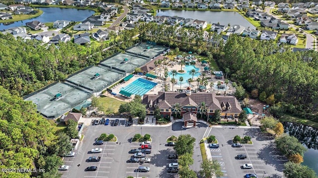 aerial overview of property's location featuring nearby suburban area, a nearby body of water, and a pool area