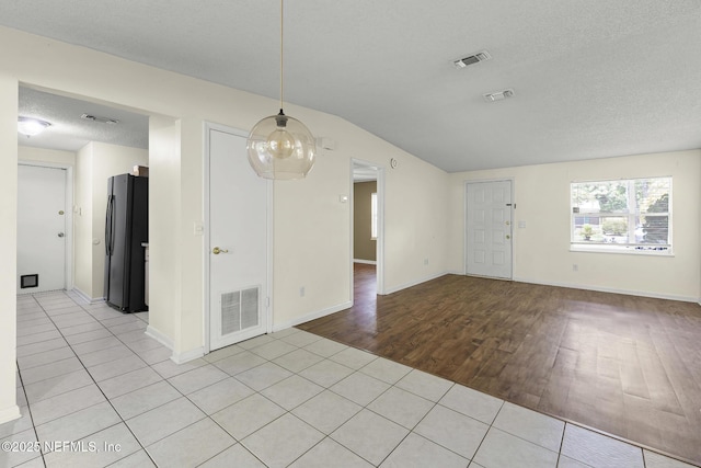 11437 Ricky Way, Jacksonville, FL 32223 - spare room featuring light wood-style flooring, a textured ceiling, vaulted ceiling, and baseboards