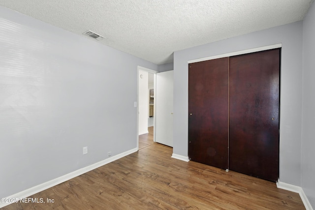 11437 Ricky Way, Jacksonville, FL 32223 - unfurnished bedroom with wood finished floors, baseboards, a closet, and a textured ceiling