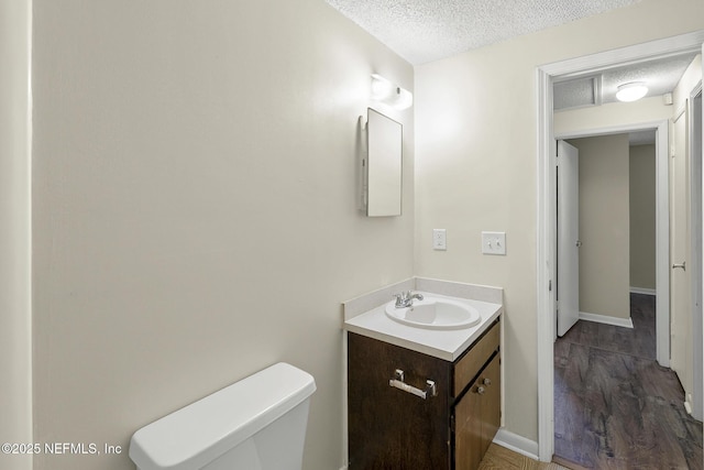 11437 Ricky Way, Jacksonville, FL 32223 - bathroom featuring a textured ceiling, vanity, toilet, wood finished floors, and baseboards