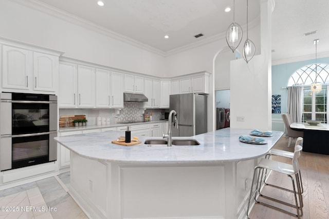 400 Big Tree Rd, Ponte Vedra Beach, FL 32082 - kitchen with stainless steel appliances, under cabinet range hood, washer and dryer, a sink, and white cabinets