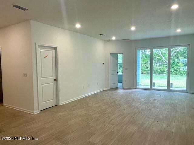spare room with wood finished floors, baseboards, and recessed lighting