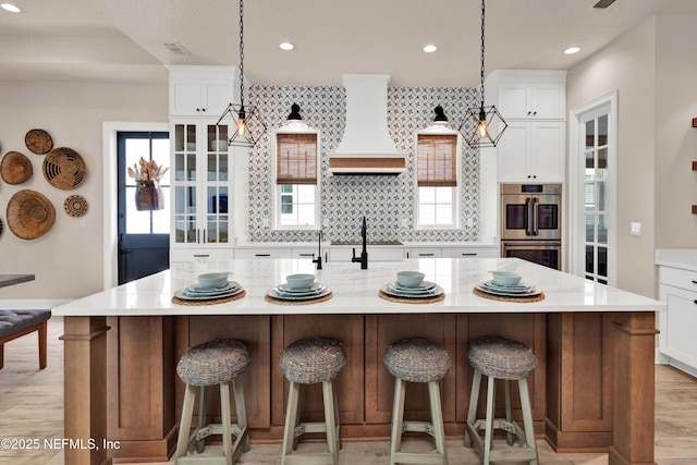37 High Ridge Pt, Ponte Vedra, FL 32081 - kitchen featuring premium range hood, stainless steel double oven, light countertops, decorative backsplash, and a large island with sink