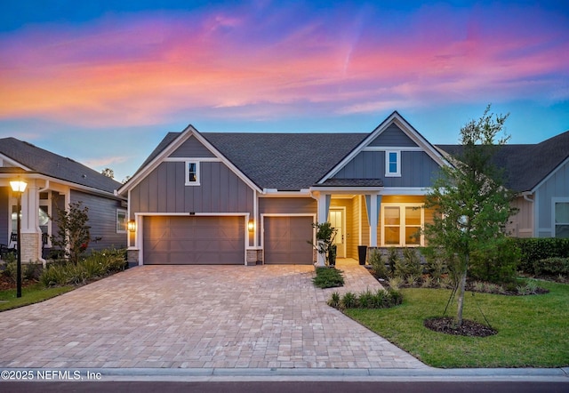 craftsman inspired home with board and batten siding, decorative driveway, stone siding, and a front lawn