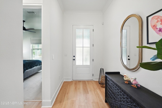 foyer entrance featuring light wood-type flooring, healthy amount of natural light, crown molding, and ceiling fan