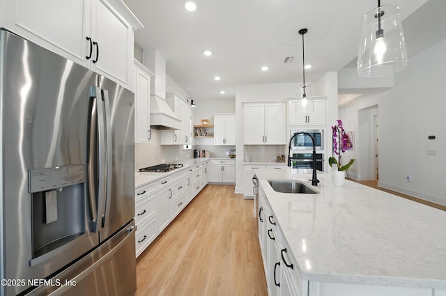 kitchen featuring stainless steel appliances, a large island with sink, a sink, decorative backsplash, and open shelves