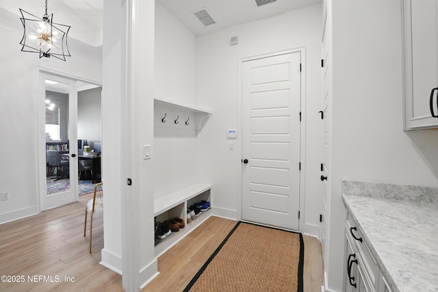 mudroom with light wood finished floors, a chandelier, and baseboards