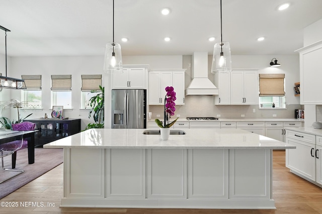 kitchen featuring stainless steel fridge, premium range hood, a sink, gas cooktop, and white cabinets