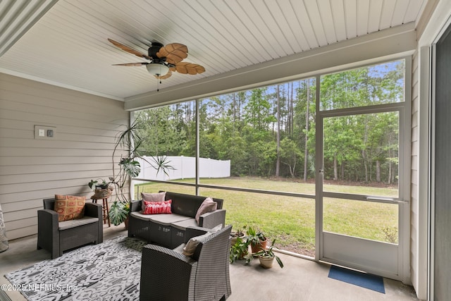 sunroom / solarium with an outdoor living space, ceiling fan, and view of scattered trees