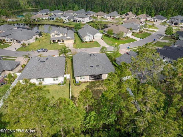 aerial perspective of suburban area featuring a forest and a nearby body of water