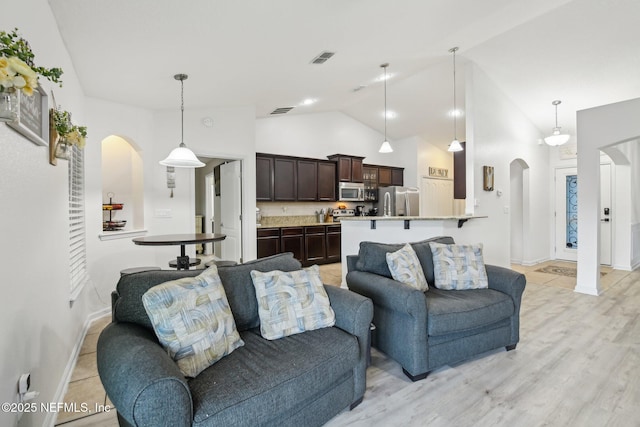 3228 Deer Creek Dr, Middleburg, FL 32068 - living room with arched walkways, high vaulted ceiling, baseboards, and light wood-type flooring