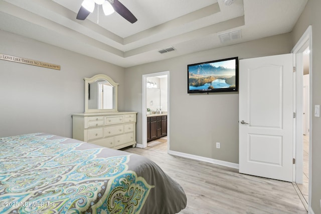 3228 Deer Creek Dr, Middleburg, FL 32068 - bedroom with a tray ceiling, light wood-style floors, baseboards, and ensuite bath