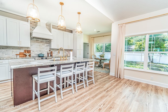 4282 Wolfe Dr, Macclenny, FL 32063 - kitchen with a sink, a breakfast bar area, light wood-style flooring, backsplash, and a center island with sink
