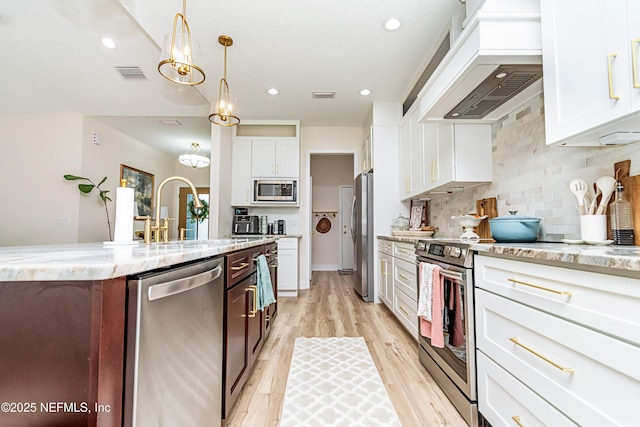 4282 Wolfe Dr, Macclenny, FL 32063 - kitchen featuring appliances with stainless steel finishes, custom exhaust hood, light wood finished floors, white cabinets, and recessed lighting