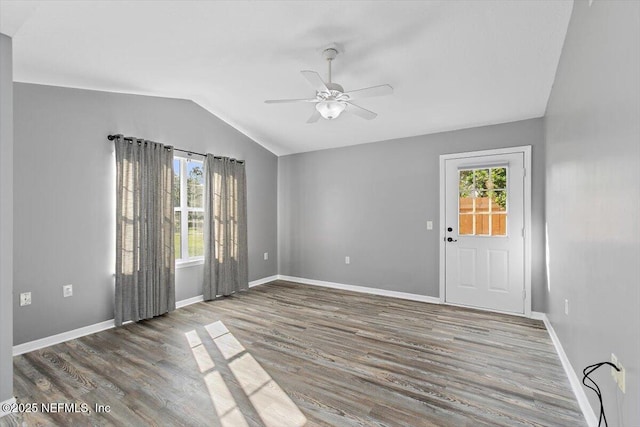 empty room featuring vaulted ceiling, a ceiling fan, wood finished floors, and baseboards