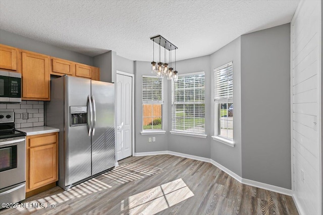 kitchen with stainless steel appliances, wood finished floors, tasteful backsplash, light countertops, and baseboards