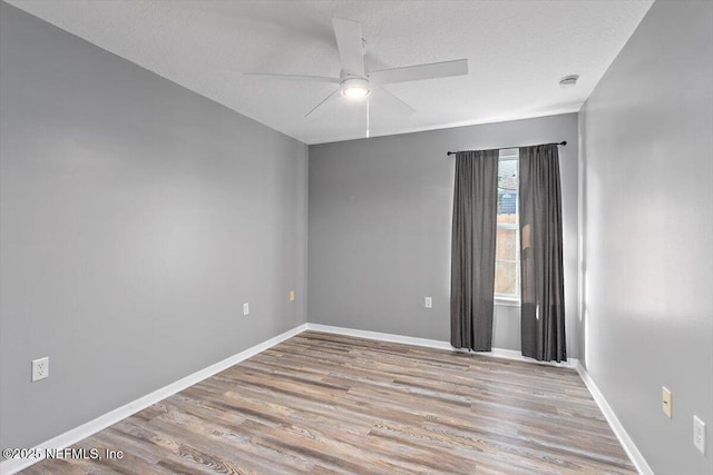 unfurnished room featuring wood finished floors, ceiling fan, baseboards, a textured ceiling, and a smoke detector