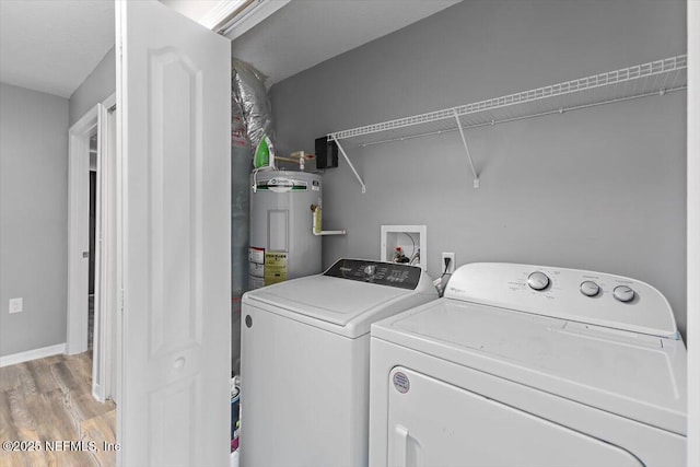 laundry room with electric water heater, washer and clothes dryer, light wood-style flooring, and baseboards