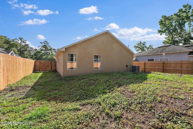 rear view of property featuring a fenced backyard, central air condition unit, and a gate