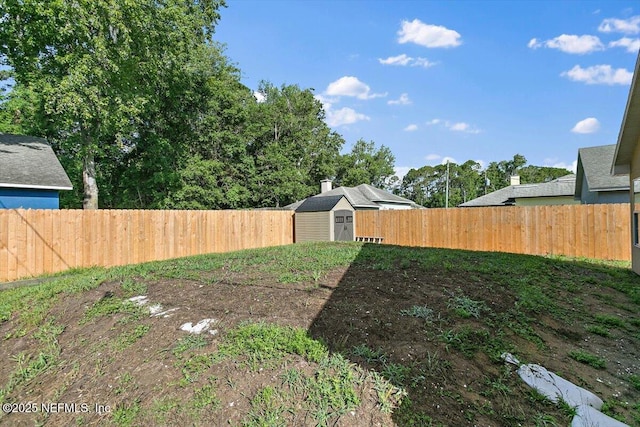 fenced backyard featuring a storage unit and an outbuilding