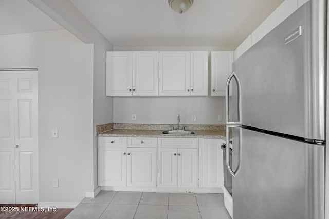 944 Bunker Hill Blvd, Jacksonville, FL 32208 - kitchen featuring freestanding refrigerator, a sink, white cabinets, and light tile patterned floors