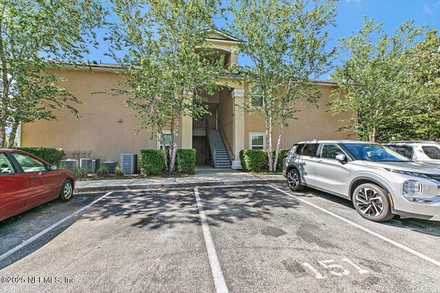 view of property with uncovered parking, central AC, and stairs