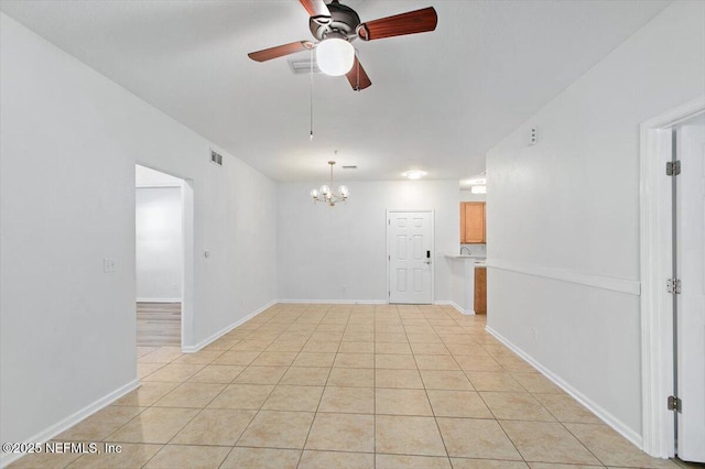 spare room with a chandelier, ceiling fan, light tile patterned floors, and baseboards