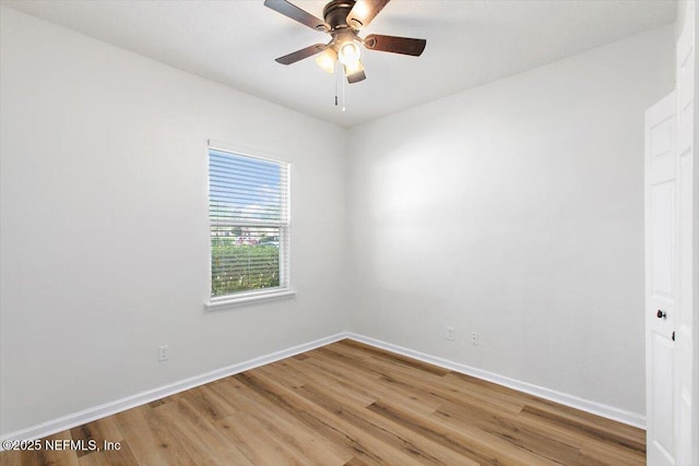 spare room featuring baseboards, light wood-style floors, and a ceiling fan