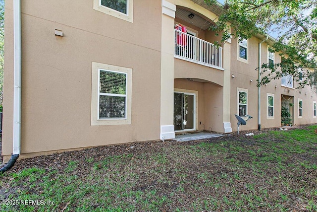 rear view of property with stucco siding and a balcony