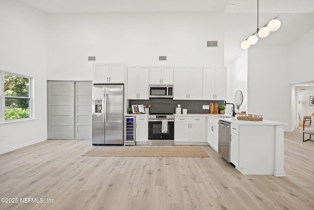550 Robles Ln, Ponte Vedra Beach, FL 32082 - kitchen featuring stainless steel appliances, a high ceiling, wine cooler, a peninsula, and light wood-style floors