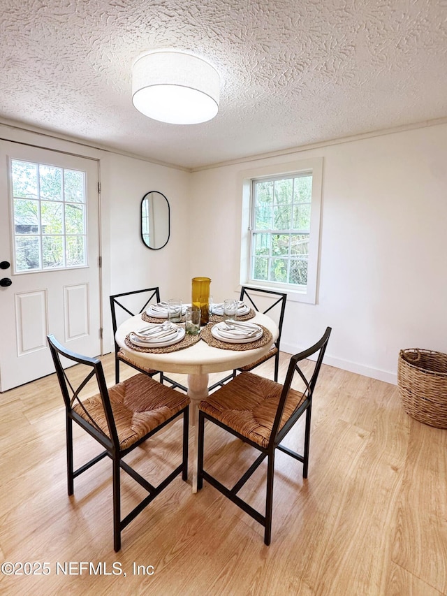 dining area featuring light wood-style flooring, a textured ceiling, and healthy amount of natural light