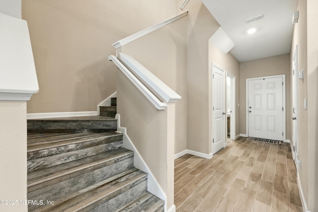 foyer entrance featuring light wood-type flooring, stairs, and baseboards