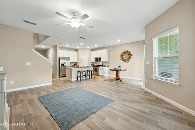 living area featuring ceiling fan, light wood finished floors, baseboards, and recessed lighting