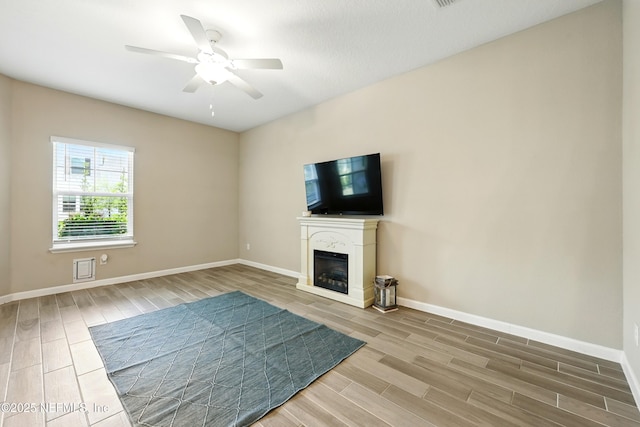 unfurnished living room with wood tiled floors, baseboards, and a ceiling fan