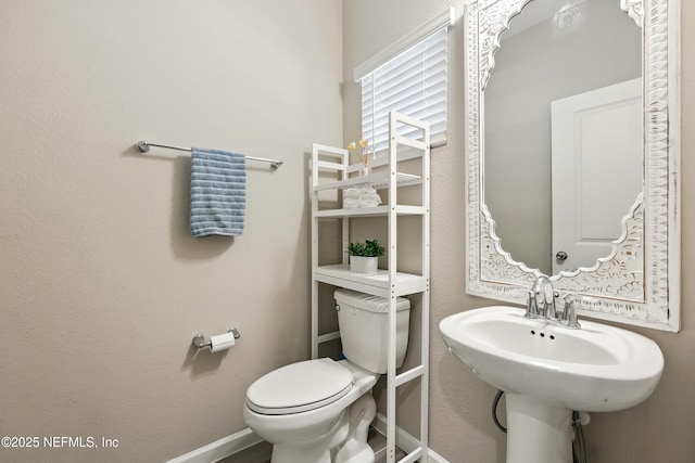 bathroom with toilet, baseboards, and a sink