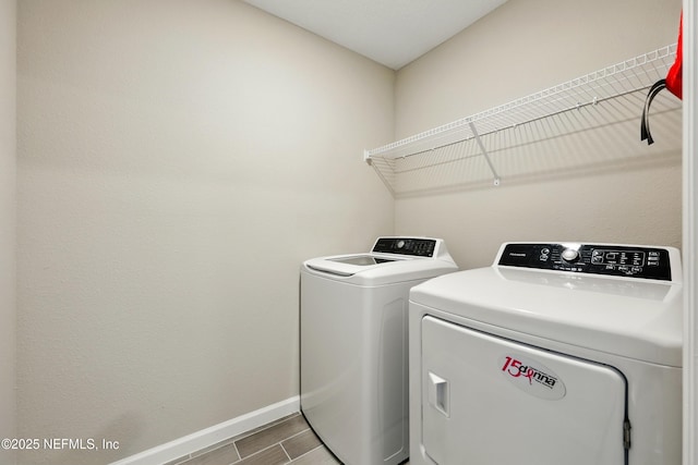 clothes washing area featuring washing machine and dryer, baseboards, and wood finished floors