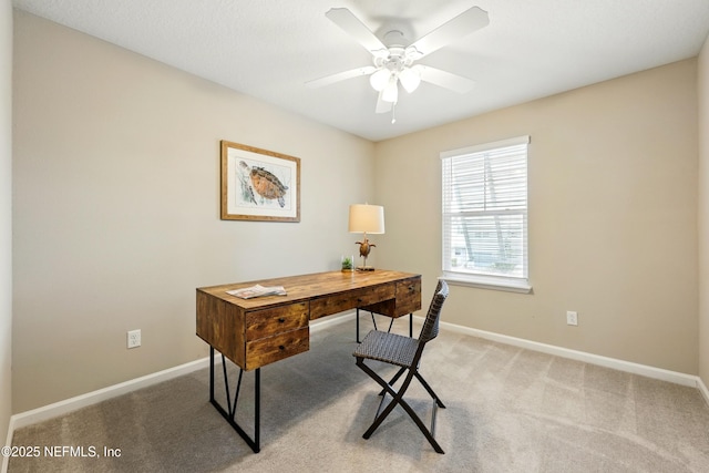 carpeted office space featuring baseboards and ceiling fan