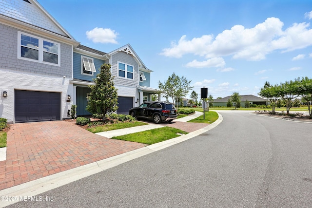 view of front of house featuring decorative driveway, a garage, and a residential view