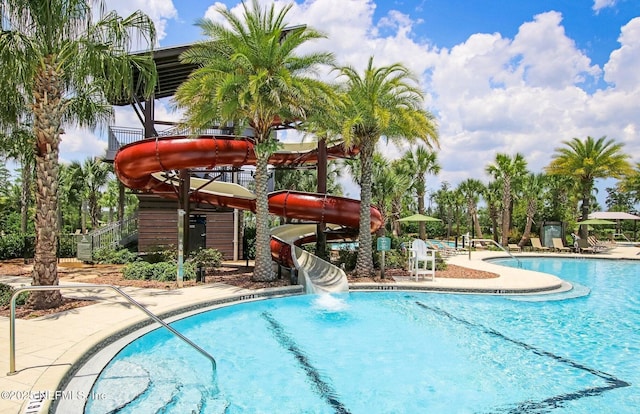 community pool with a water slide, stairway, and a patio area