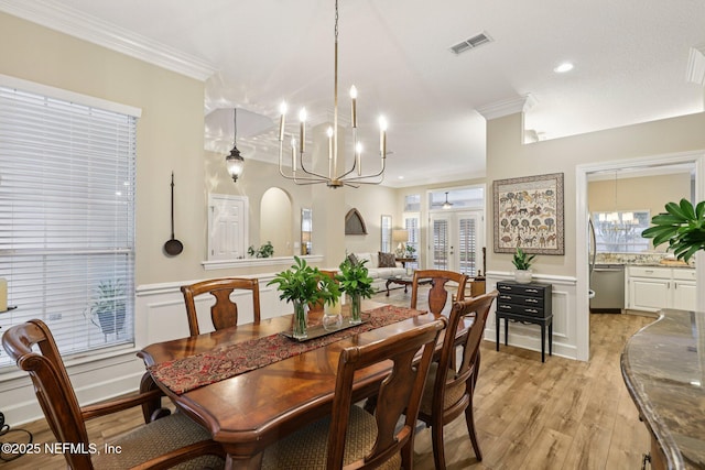 641 Thornwood Ln, Orange Park, FL 32073 - dining room with a chandelier, crown molding, light wood finished floors, wainscoting, and a decorative wall