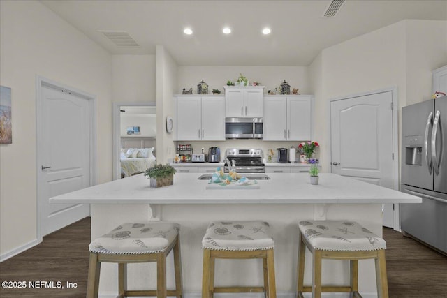4101 Spring Creek Ln, Middleburg, FL 32068 - kitchen with appliances with stainless steel finishes, a kitchen bar, dark wood finished floors, white cabinetry, and recessed lighting