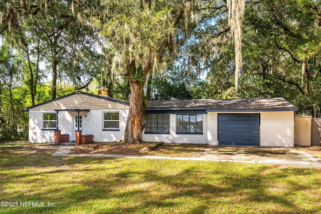 view of front facade with concrete block siding, a front yard, a garage, driveway, and a chimney